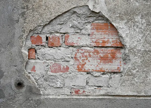 Yıpranmış duvar vitrinlerinin bir parçası harç parçalarının yanında tuğlaları da açığa çıkarıyor. Yüzey gölgelerinin dokusu ve yaşı kentsel bozulmayı yansıtıyor.