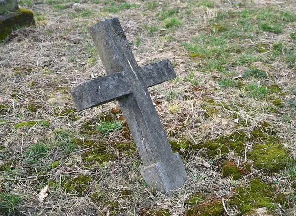 Yıpranmış haç, kısmen çimlerle ve yosunlarla kaplı bir mezara eğiliyor. Zamanın nasıl geçtiğini gösteriyor. 