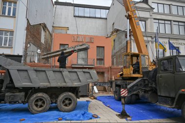 Uzhhorod, Ukrayna - 14 Mart 2025: Otel rekonstrüksiyonu sırasında bir inşaat alanında ağır ekipman taşıyan büyük vinç. İşçiler görev ilerledikçe uzaktan izlerler 