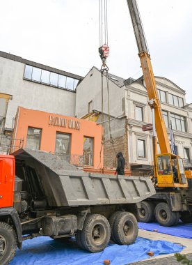 Uzhhorod, Ukrayna - 14 Mart 2025: İnşaat ekibi şehir ortamındaki yıkılmış bir yapının enkazlarını temizliyor. Atık maddelerin taşınması için bölgeye yakın bir yere park edilmiş bir kamyon var.