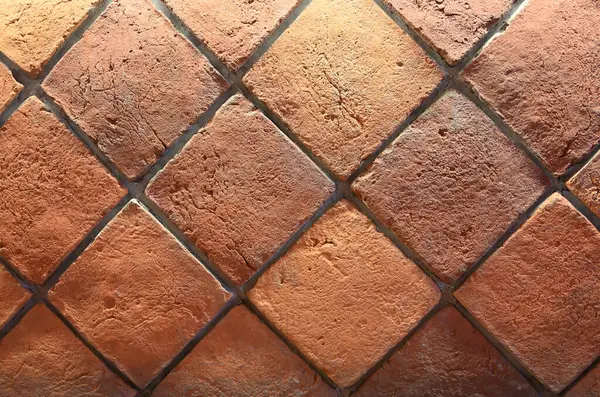 Elmas desenli terracotta fayanslarının yakın görüntüsü zengin toprak tonlarını ve desenli yüzeylerini vurguluyor, genellikle kırsal tasarımlarda kullanılır.