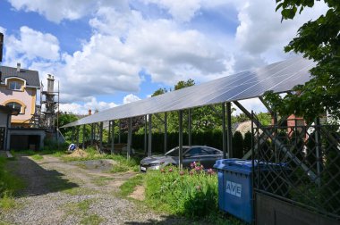 Uzhhorod, Ukrayna - 12 Mayıs 2025: Güneş panellerinin sıraları yenilenebilir enerji çözümleri sergilenen bir konut bahçesinde metal bir yapıya monte edildi