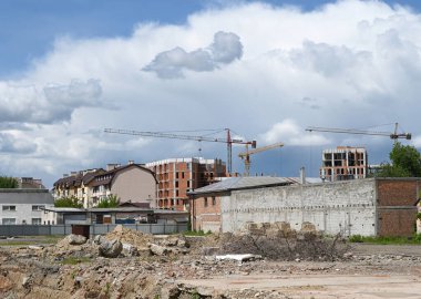 Uzhhorod, Ukrayna - 12 Mayıs 2025: İnşaat vinçleri gelişmekte olan bir kentsel alan üzerinde kule, yeni inşa edilmiş yapıları sergiliyor dağınık bulutlar ve açık mavi bir gökyüzü karşı