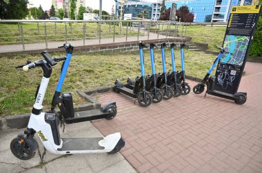 Uzhhorod, Ukrayna - 12 Mayıs 2025: Bir şehir parkının yakınına düzgün park edilmiş yedi elektrikli scooter, Uzhhorod 'daki yerli ve turistler için elverişli bir ulaşım aracı sunuyor