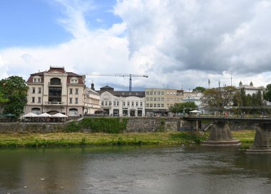 Uzhhorod, Ukrayna - 12 Mayıs 2025: Uzhhorod 'da gün boyunca yeşil ve bulutlu gökyüzü ile tarihi binaların liman manzarası