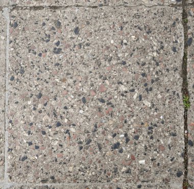 Yapılandırılmış beton kaldırımda çeşitli renkli taşlar ve toplamlar yer alıyor, parlak gün ışığı altında kentsel tasarım unsurları sergileniyor