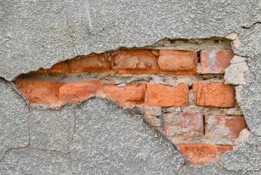 Çatlaklar ve düzensizlikler yıpranmış bir duvarda açık tuğla olduğunu gösteriyor. Havan topu, gün ortasının yumuşak ışığıyla aydınlatılan yaşlanma ve doğal aşınma belirtilerini gösteriyor.