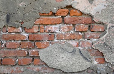 Çatlaklar ve düzensizlikler yıpranmış bir duvarda açık tuğla olduğunu gösteriyor. Havan topu, gün ortasının yumuşak ışığıyla aydınlatılan yaşlanma ve doğal aşınma belirtilerini gösteriyor.