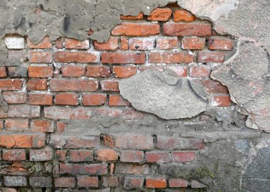 Çatlaklar ve düzensizlikler yıpranmış bir duvarda açık tuğla olduğunu gösteriyor. Havan topu, gün ortasının yumuşak ışığıyla aydınlatılan yaşlanma ve doğal aşınma belirtilerini gösteriyor.