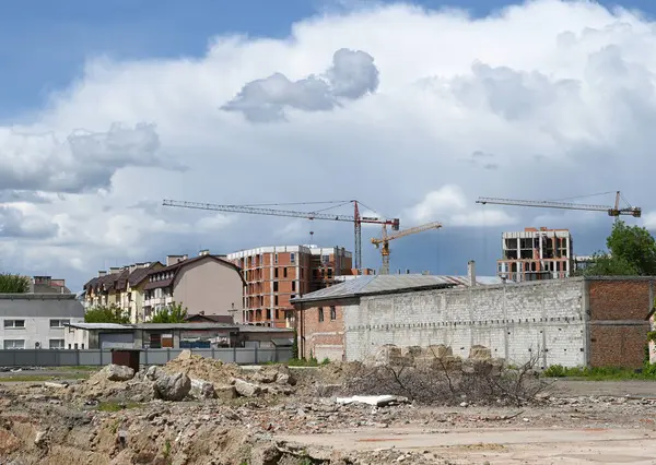 Uzhhorod, Ukrayna - 12 Mayıs 2025: İnşaat vinçleri gelişmekte olan bir kentsel alan üzerinde kule, yeni inşa edilmiş yapıları sergiliyor dağınık bulutlar ve açık mavi bir gökyüzü karşı