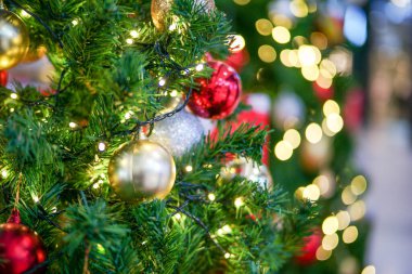Arka planda Bokeh ışıkları olan Noel ağacına süslenmiş altın topa odaklan. Noel festivalinde parti ve kutlama