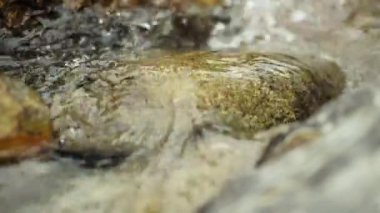 Water flows and falls over the layers of stones in the natural stream.