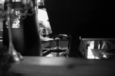 Selective focus on the metal equipment for manually pressing the coffee powder for making the fresh coffee at the cafe. Picture processed in monochrome concept