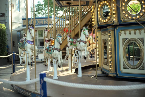 Motioned blurred picture of horse of the carousel with defocused horses and bokeh lights in background.