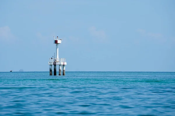 stock image The concrete structure of lighthouse in the sea with horizontal line and blue sky in background