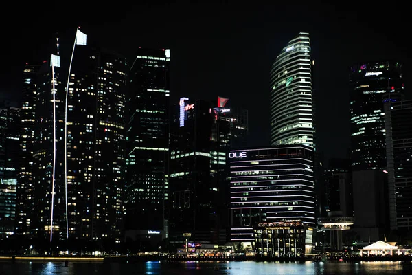 Singapur: 20 Ağustos 2023 'te iş bölgesinde ışıklandırmalı ve ön planda marinalı yüksek binalar