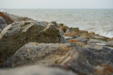 Bulanık ön plan ve deniz manzaralı taşın pürüzlü yüzeyine seçici odak
