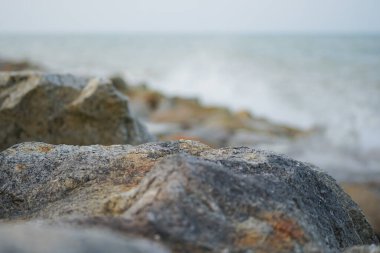 Bulanık ön plan ve deniz manzaralı taşın pürüzlü yüzeyine seçici odak
