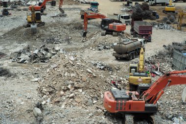 İnşaat alanının zemininde çalışan kazıcıların çoğu, binanın yıkımından sonra enkazı kaldırırken,