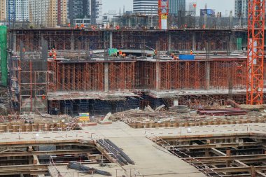 İşçiler inşaat halindeki binada çalışıyorlar ve içeride birçok yapı iskelesi var.