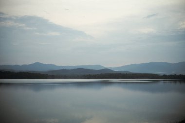 Önünde barışçıl bir göl olan dağların birçok katmanının manzarası..