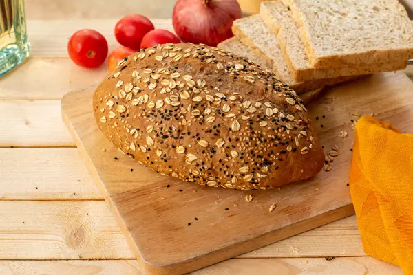 stock image Whole grain bread with sesame seeds on wooden table, closeup.