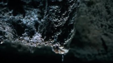 Slow motion dolly shot of drops dripping from rocks in cave in Croatia