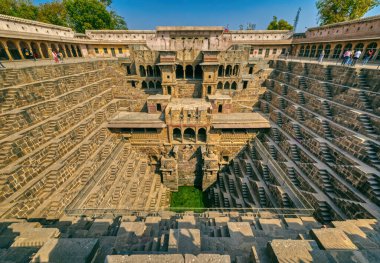 ABHANERI, INDIA - MARCH 4 2018: A view across the giant Ancient Chand Baori Stepwell in the Historical Village Abhaneri in Rajasthan state in India. clipart