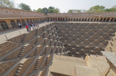 ABHANERI, INDIA - MARCH 4 2018: A view across the giant Ancient Chand Baori Stepwell in the Historical Village Abhaneri in Rajasthan state in India. clipart