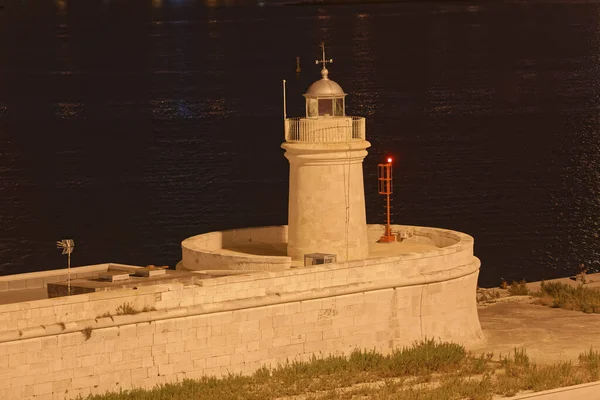 Old stone lighthouse by night in the Bari city port, Italy.