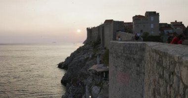 DUBROVNIK, CROATIA - 21 Ağustos 2019: Günbatımında eski kasaba duvarlarını ziyaret eden turistler.