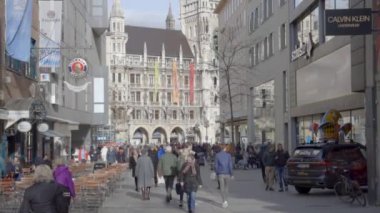 MUNICH, Almanya - 2 Şubat 2020: Turistler şehrin merkezindeki Marienplatz Meydanı 'ndaki tarihi belediye binasını geziyorlar. yukarı doğru eğiliyor