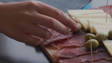 Yerel Hırvat lezzetleri tepsisinden bir dilim prosciutto alan bir elin yakın çekimi.