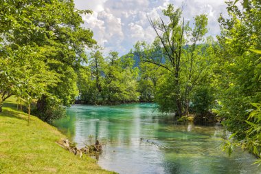 Serene view of the Una River coursing through the bustling city center of Bihac, creating a beautiful juxtaposition of natural beauty and urban life.