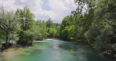 Serene view of the Una River coursing through the bustling city center of Bihac, creating a beautiful juxtaposition of natural beauty and urban life. Slowmotion video.