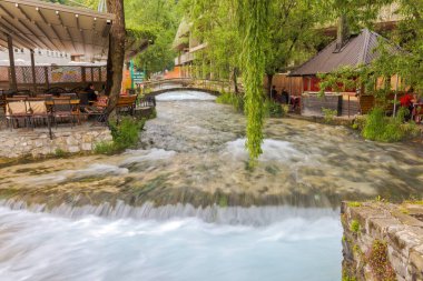 TRAVNIK, BOSNIA VE HERZEGOVINA - 3 Haziran 2023: Huzurlu Plava Voda Pınarı yaya köprüsünün altından akar ve şehre doğru çağlayarak ilerler..