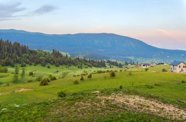 Bosna-Hersek 'in Travnik kentindeki Vlasiç Dağı eteklerinde yuva yapmış yemyeşil çayırların nefes kesici panoramik manzarası.