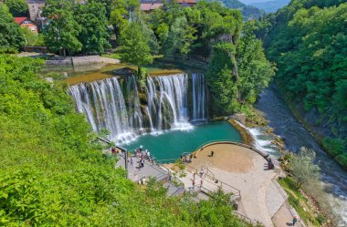 JAJCE, BOSNIA VE HERZEGOVINA - 2 Haziran 2023: Pliva ve Vrbas nehirlerinin Pliva Şelalesi 'nde birleştiği görkemli manzarayı yakalayan platodaki turistler.