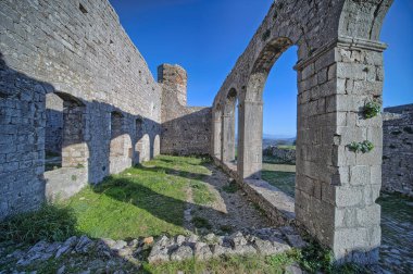 Arnavutluk 'un Şkoder kentindeki Rozafa kalesinin zirvesinde hem cami hem de kilise olarak hizmet veren bir binanın mimari kalıntıları, sütunlar ve kemerler sergileniyor.