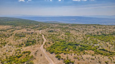 Mostar Platosu 'nun sert manzaralarından geçen yılansı bir yolun havadan görüntüsü..