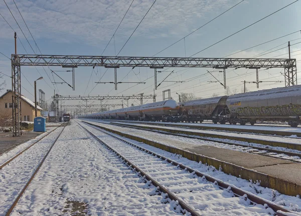 2023年1月25日 白雪覆盖的铁路轨道在乌云密布的天空下与货运列车一起延伸至远方 — 图库照片