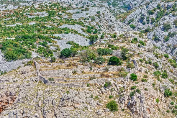 Scenic view of the limestone terrain and sparse vegetation at the foot of the majestic Velebit Mountain in Croatia.