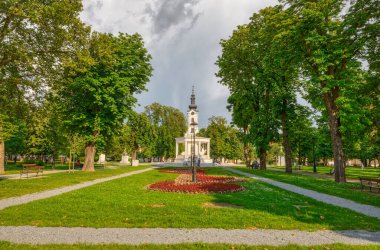 BJELOVAR, CROATIA - 2 Haziran 2019: Avila 'lı eski barok katedrali Teresa kasaba merkezi Eugen Kvaternik Meydanı' ndaki Central Park manzaralı.