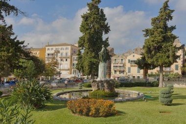 CORFU, GREECE - 21 Ekim 2022: Heykeltraş Pavlos Prosalentis tarafından yapılan Sör Frederick Adam heykeli, bir şehir parkının yeşilliğinin ortasındaki yansıyan bir gölete karşı, hareketli bir zemin ile kurulmuştur..