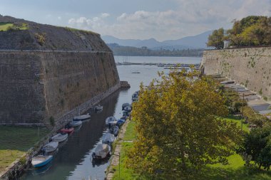 CORFU, GREECE - 21 Ekim 2022: Eski Korfu Kalesi 'nin panoramik manzarası, kanala demirlemiş tekneler ve arka planda İyon Denizi, Yunan tarihi mimarisinin güzelliğini vurguluyor