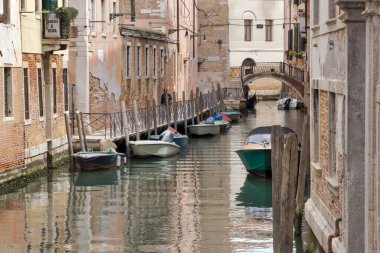 VENICE, İtalya - 11 Nisan 2023: bir kanal caddesinde kemer köprüsünden geçmek, tam anlamıyla eski kasaba cazibesinin vücut bulmuş hali..