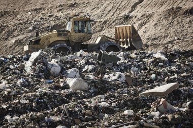Heavy machinery shredding garbage in an open air landfill. Waste