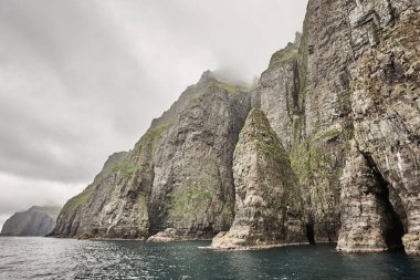 Faroe adalarında bulutlu bir günde dramatik yeşil kayalıklar. 