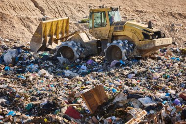 Heavy machinery shredding garbage in an open air landfill. Waste