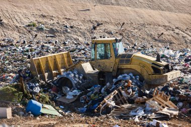 Heavy machinery shredding garbage in an open air landfill. Waste